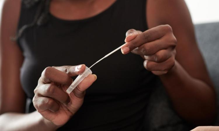 A woman holds a small vial and swab from an at-home Covid-19 test.