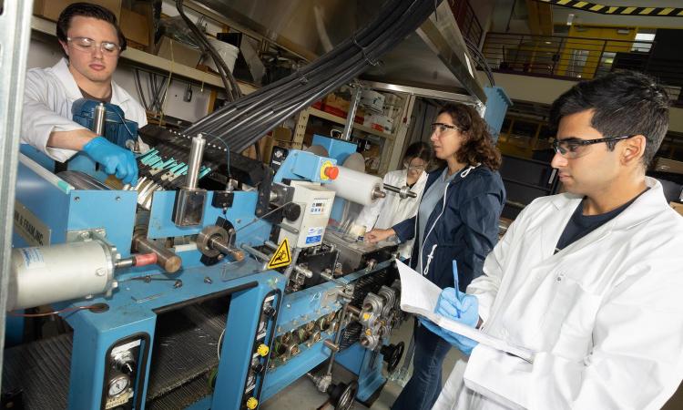 Kyriaki Kalaitzidou and students work on a polymer fiber machine in the lab.