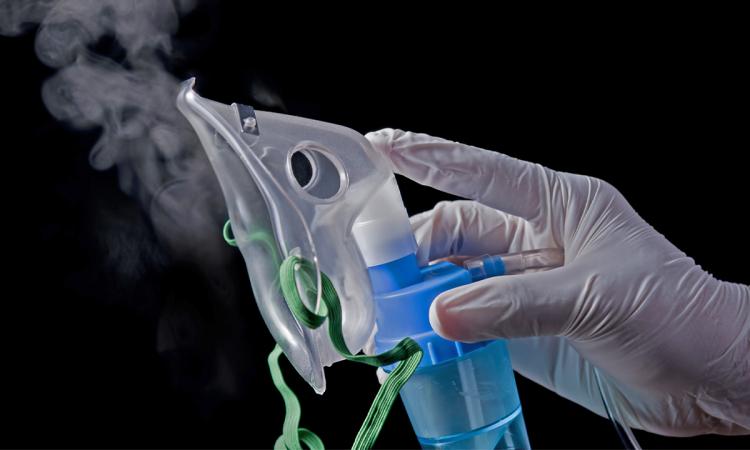 a hand holding a nebulizer mask with vapor 