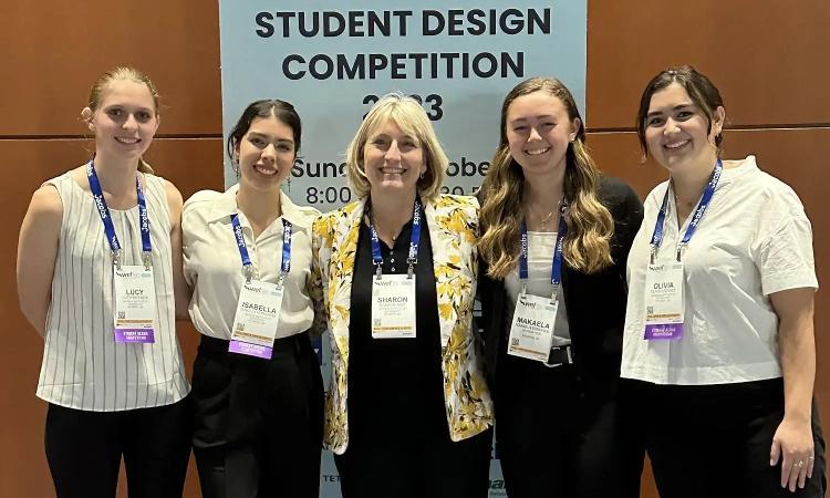 First-place winning team Lucy Bricker, Makaela Edmonds, Isabella Hernandez, and Olivia Verret with advisor Sharon Just in front of the WEFTEC Student Design Competition sign.