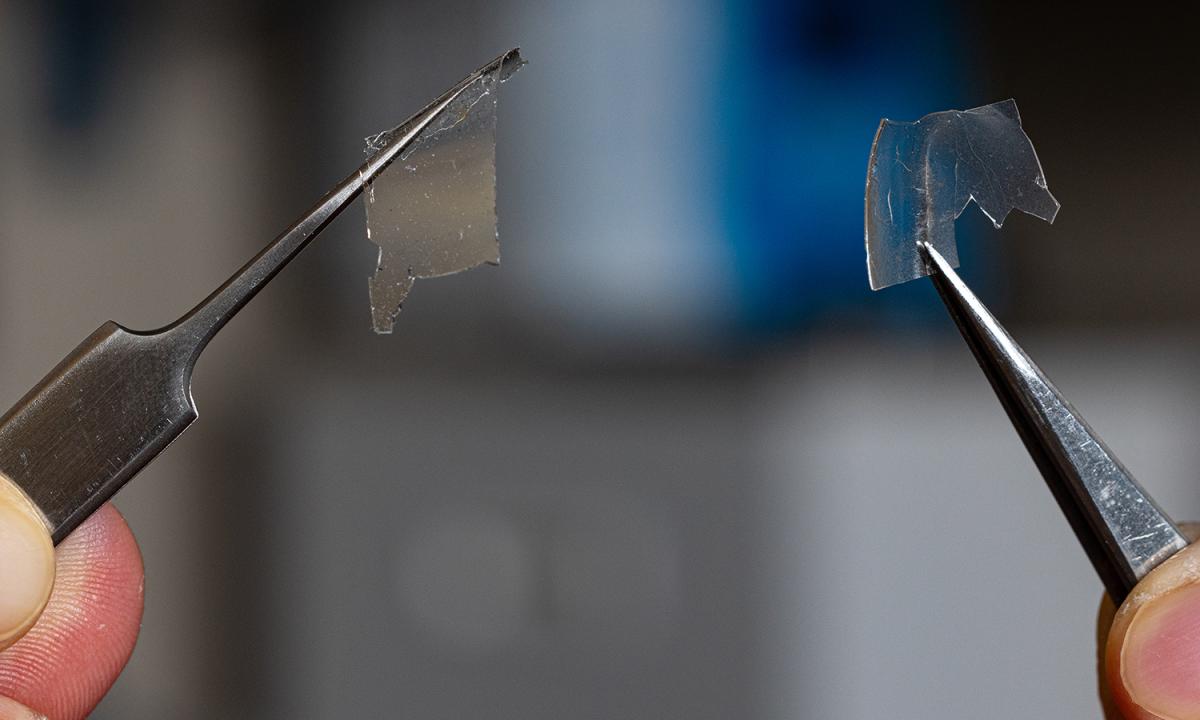 Two tweezers holding small samples of the transparent raw materials researchers used to create 3D-printed glass microstructures. (Photo: Candler Hobbs)