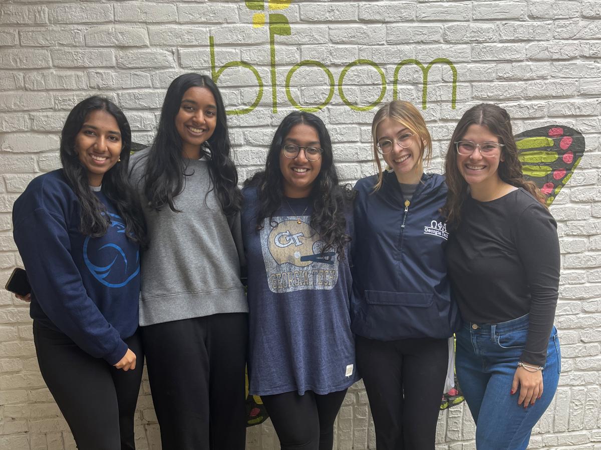 A group of five students in front of a wall with the "Bloom Closet" logo