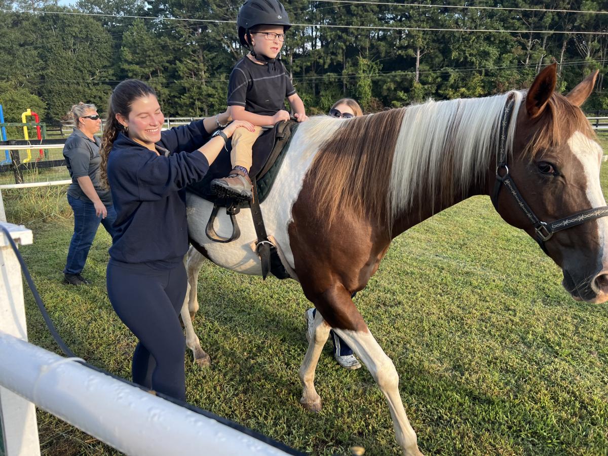 Bethanie Penna helps a child riding a horse