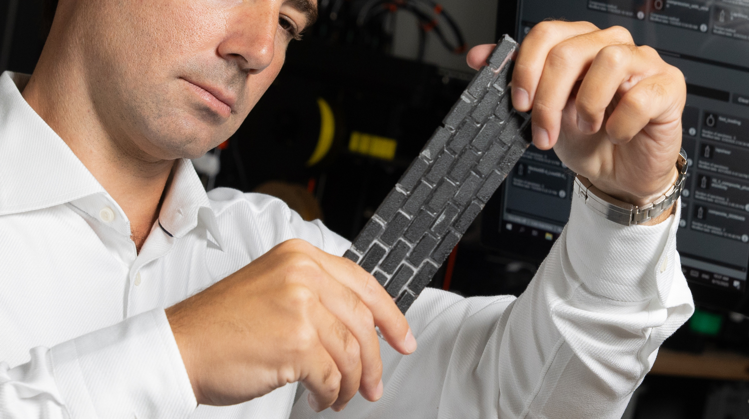 Christos Athanasiou looking at a recycled black plastic composite material