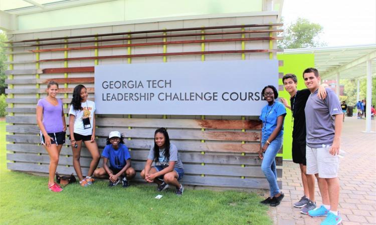 A group of students standing at the sign to the Leadership Challenge Course on campus