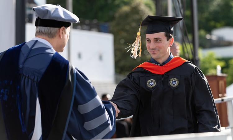 graduate shaking hands with faculty member