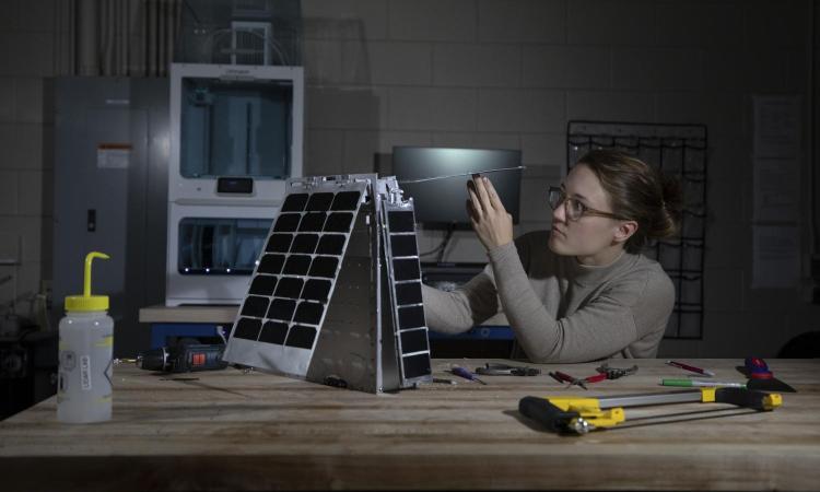 A student adjusts the Lunar Flashlight model's solar array in the makerspace