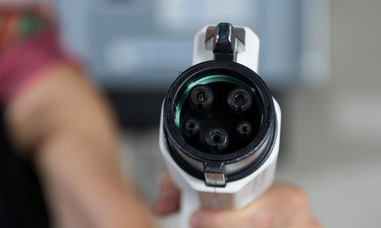 A hand holding an electric vehicle charger connector