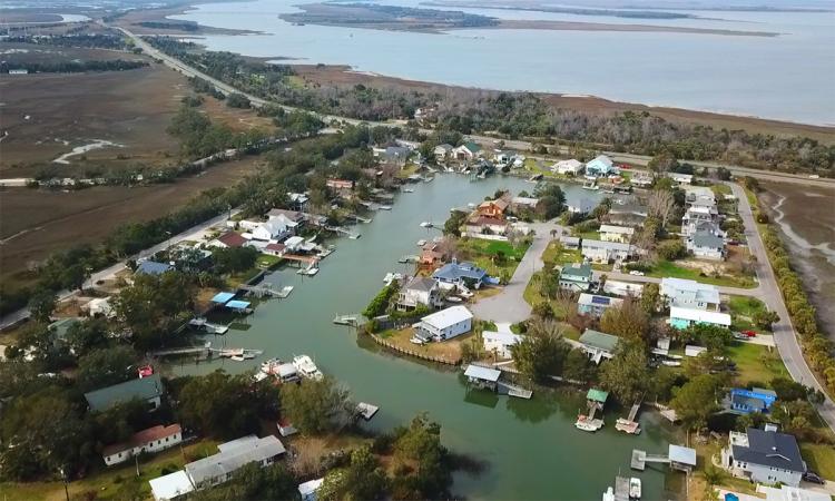 Aerial view of a coastal neighborhood with homes, canals, and the Intracoastal waterway.