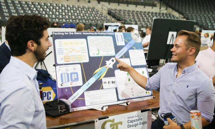 students standing next to a poster, talking to one another