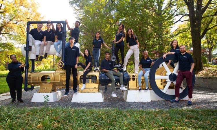 A group of Clark Scholars standing around the steam engine outside Tech Tower