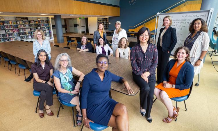 Group of 13 women sitting and standing around a table