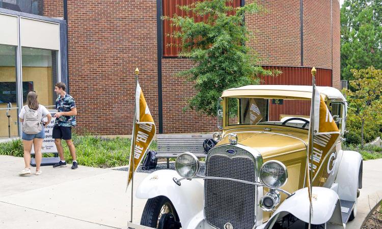 Two students walk past the Ramblin' Wreck to the Van Leer building