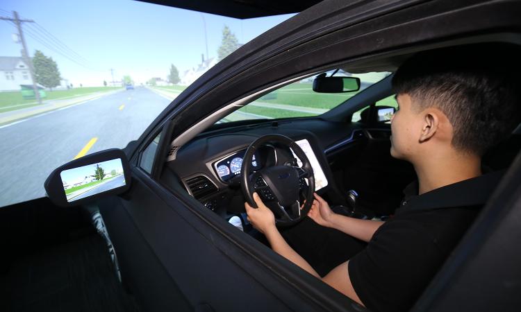 A grad student operates a full-scale driving simulator in Srinivas Peeta's lab.