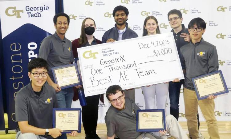 A group of eight students from the winning AE team with an oversized check