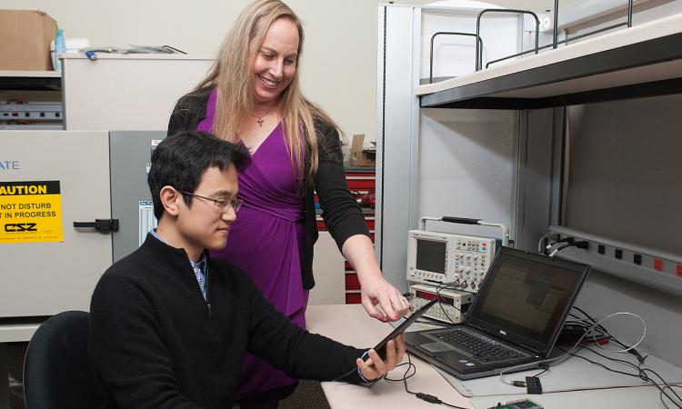 Jennifer Hasler and a student look at a field-programmable analog array system-on-chip