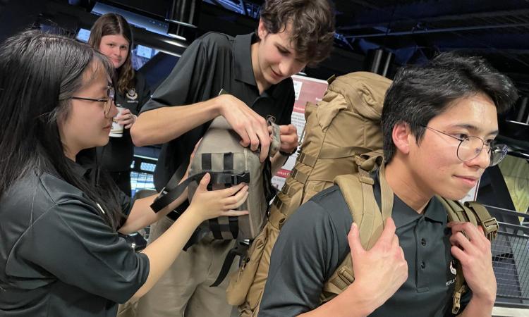 students putting a bag on a backpack