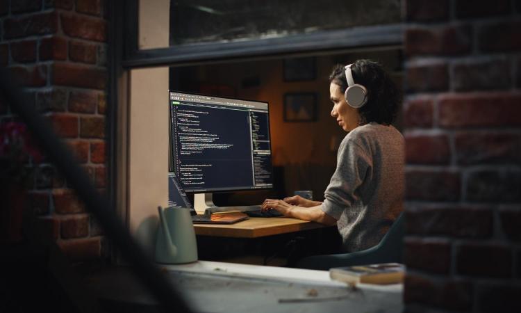 A woman wearing headphones works at a computer.