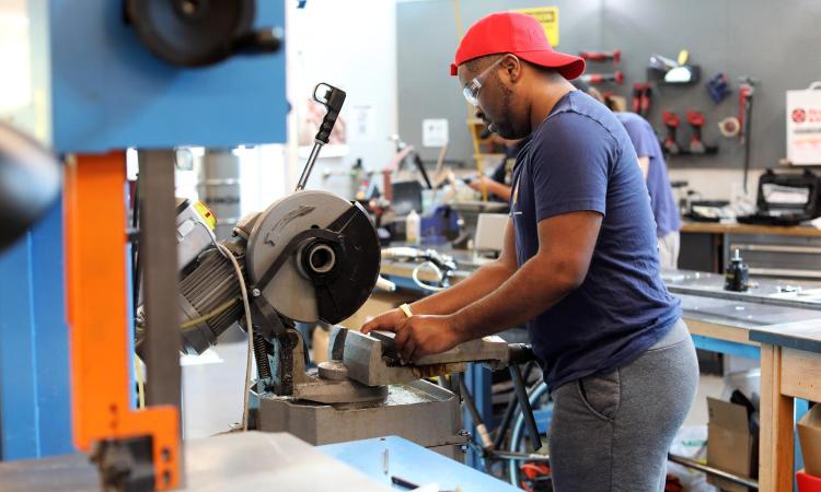 A student uses a saw in the Invention Studio