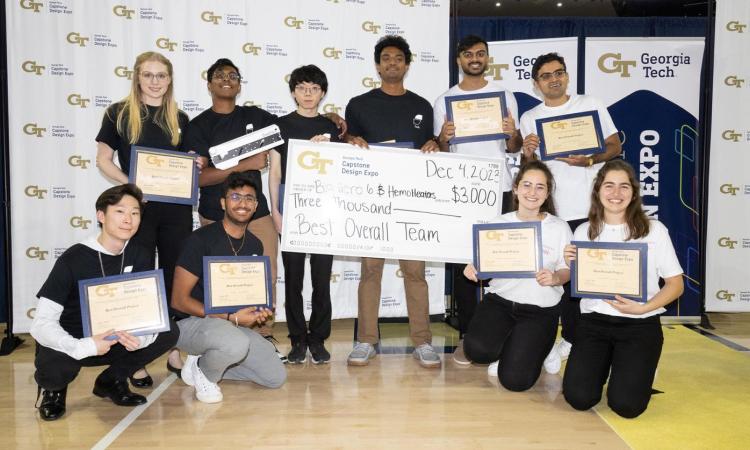 a group of students with certificates and an oversized winners check