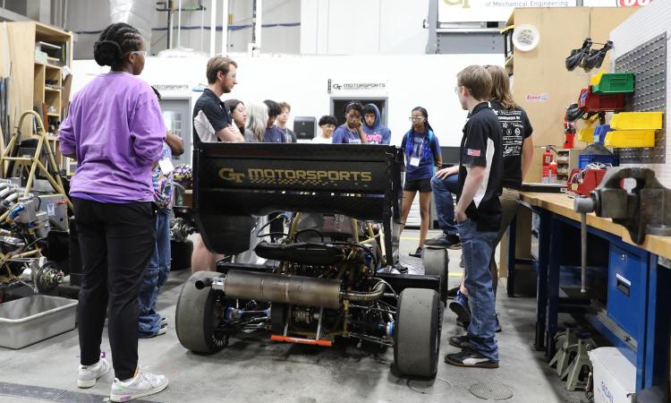 Students stand around the GT Motorsports Formula SAE competition car in the Student Competition Center.