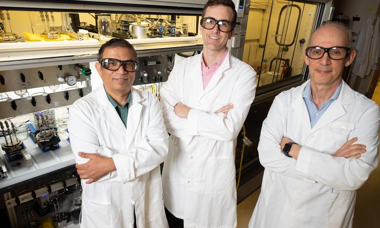 three men in lab coats stand in the lab