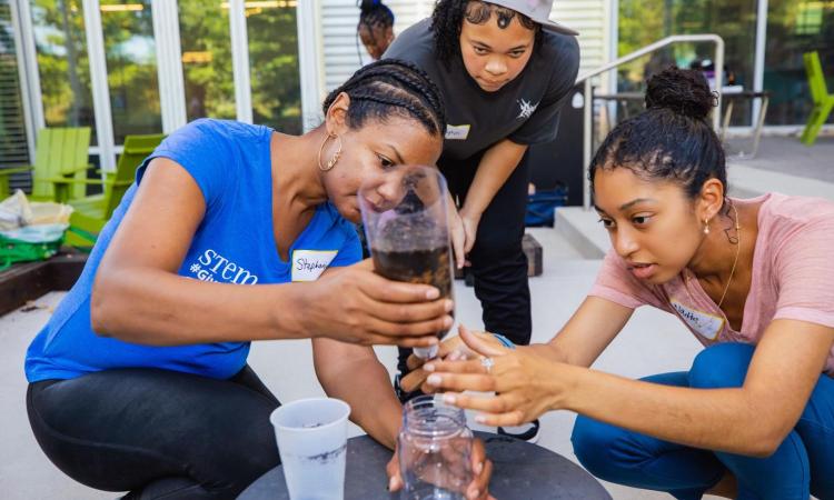 three students work with a water filter experiment