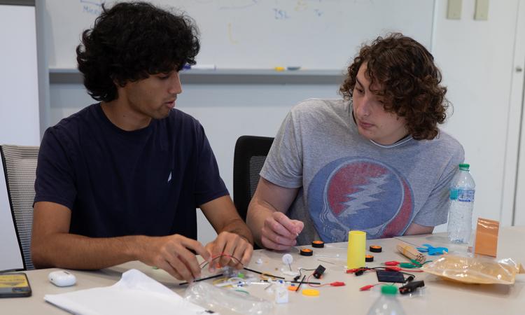 two students work with robotics electronics