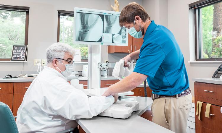 A person uses the OXOS portable X-ray device to take an image of another person's hand