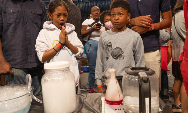 two kids with surprised look when watching experiment in beakers