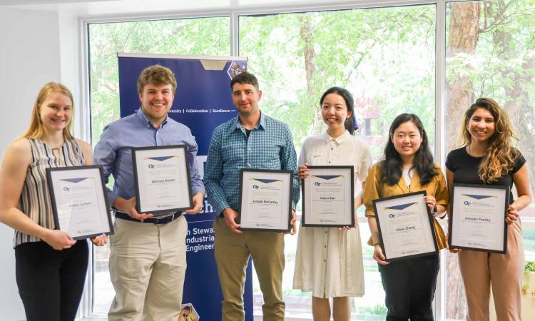 six students facing camera holding certificates