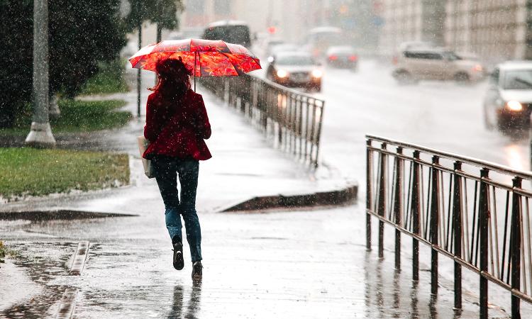 stock image of a woman with an umbrella walking in the street 