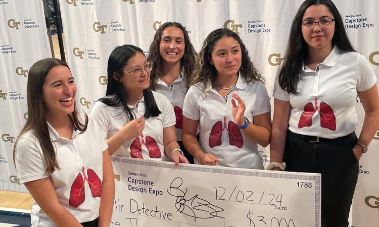 A group of students stand with an oversized winners check