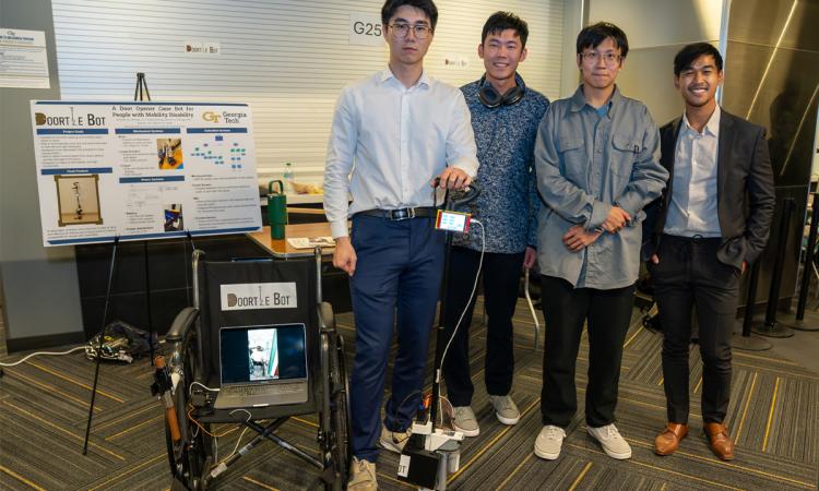 a group of students stand with a robotic cane and a computer