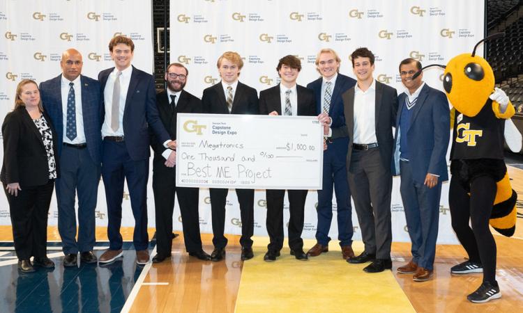 a group of people and Buzz stand with an oversized check