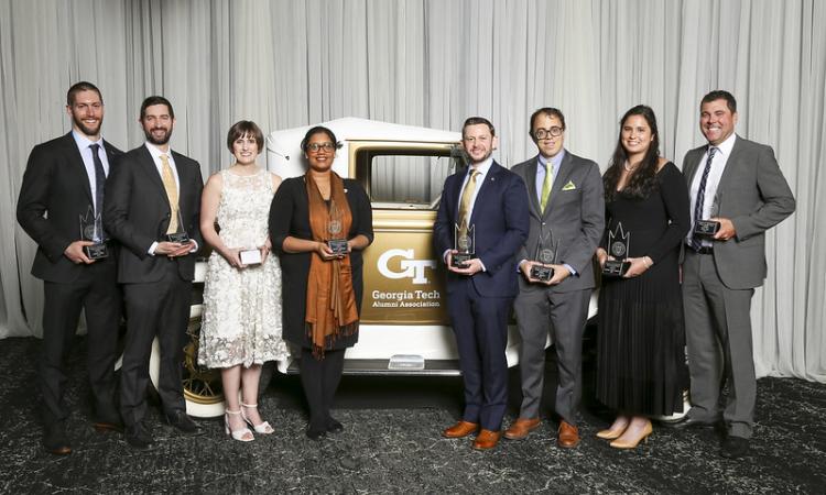 a group of people with awards stand next to the Ramblin' Wreck