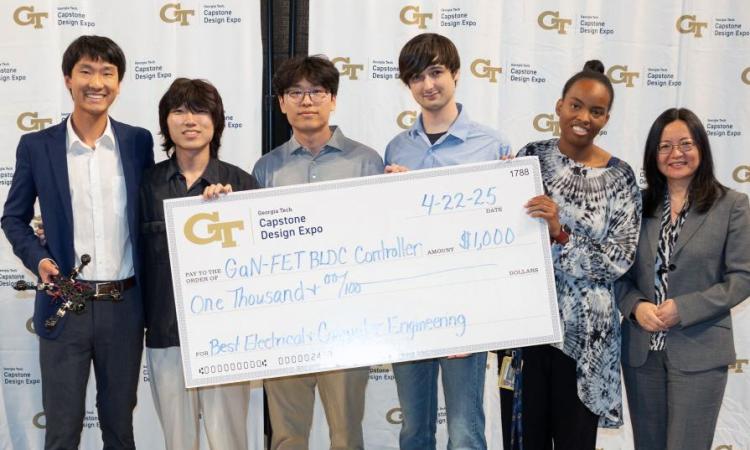 a group of students stand with a drone and an oversized winners check