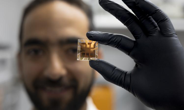 Juan-Pablo Correa-Baena holds up a solar cell in front of his face