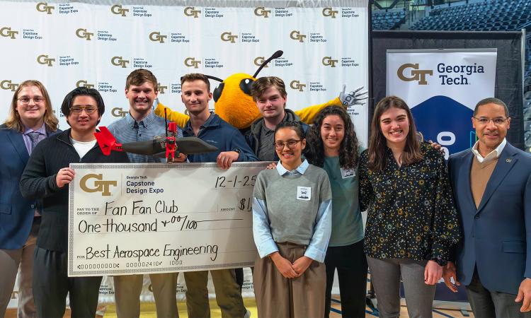 a group of students with a model aircraft and an oversized check
