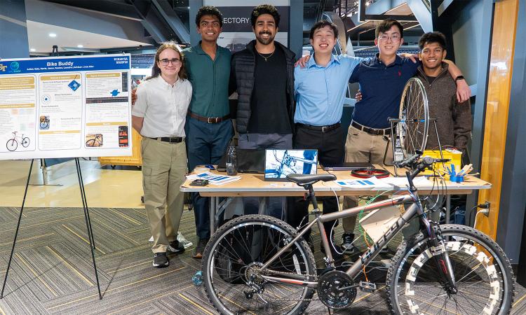 A group of people at a booth with a bike and bike parts