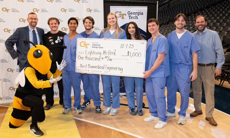 Best BME team Lightning McHeal at the fall 2025 Capstone Design expo holding their oversized check worth $1,000 alongside Buzz and faculty mentors.