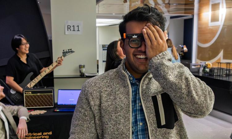 a student wears a pair of glasses and covers one eye