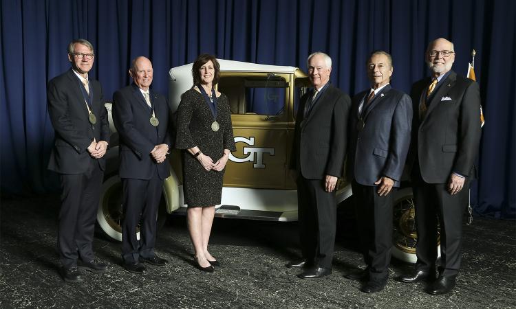 a group of people with medals stand next to the Ramblin' Wreck