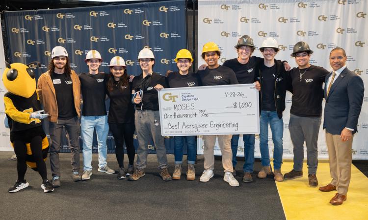 a group of people wearing hard hats pose with an oversized check and Buzz