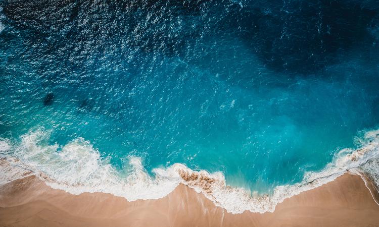 Overhead view of ocean waves lapping a sandy shore