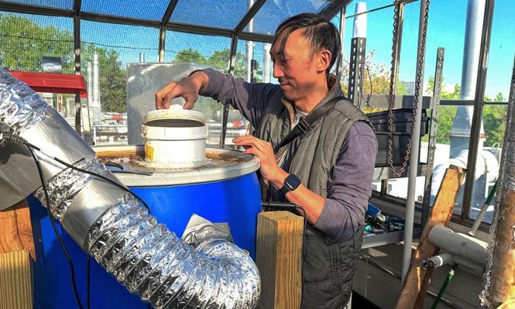 David Hu running an experimental composting unit inside a greenhouse on top of a building at Georgia Tech.