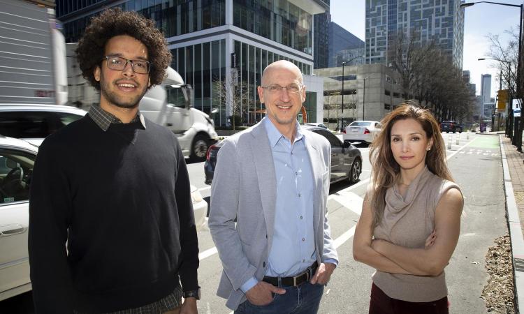 Michael Thomas, John Taylor, and Neda Mohammadi stand in front of traffic