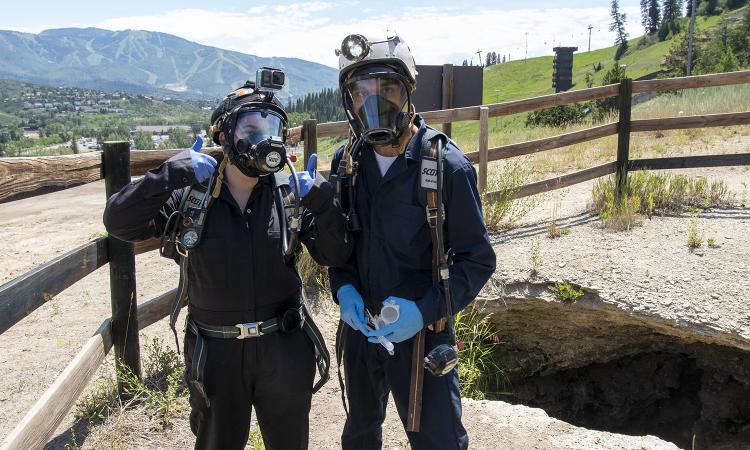 Emily Kaufman and Darshan Chudasama in protective gear at the entrance of the cave