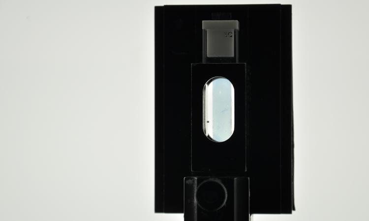A strip of transparent conductive polymer held in a square black holder with an oval window in the middle. (Photo Courtesy: James Ponder)
