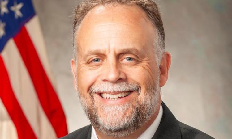 Shawn Quinn headshot with U.S. flag in the background